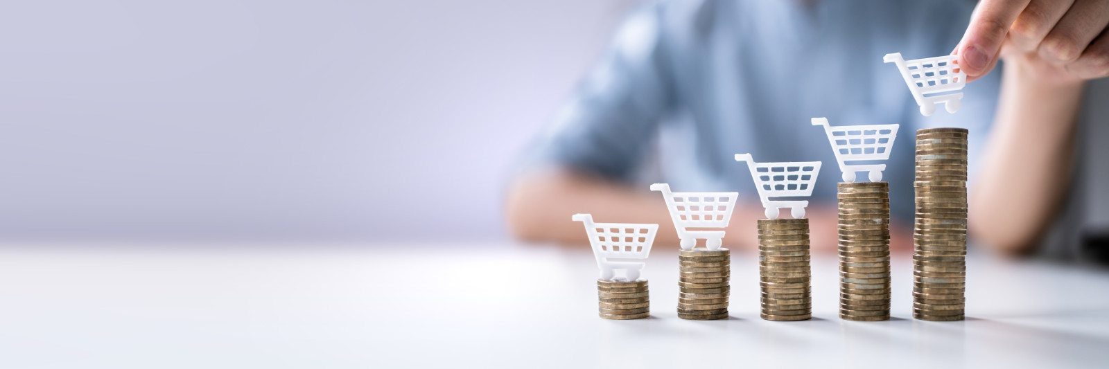 Mehre Münzstapel mit einem kleinen Einkaufswagen ob drauf